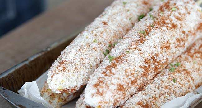 garnishing mexican street corn with cilantro