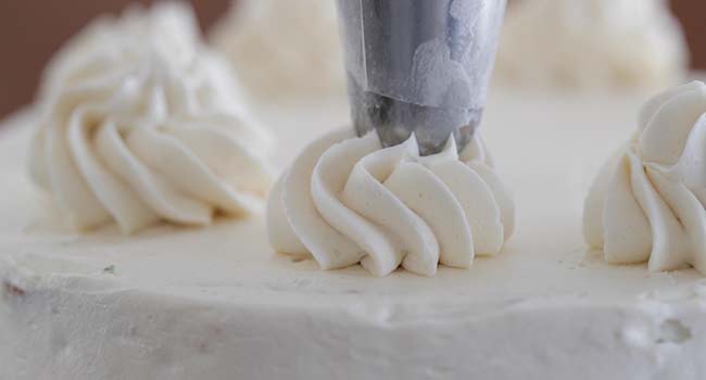 piping buttercream onto a cake