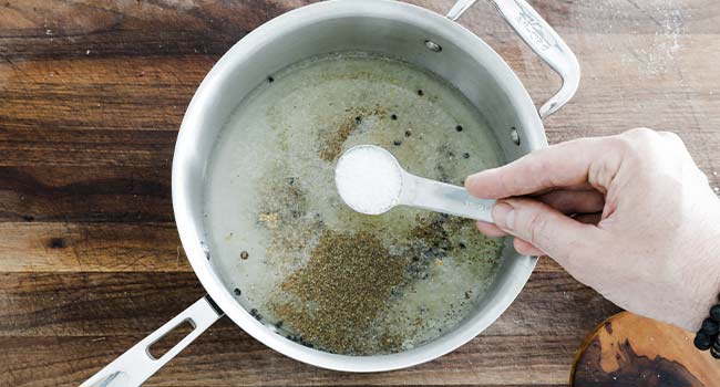 adding salt to a pot of vinegar