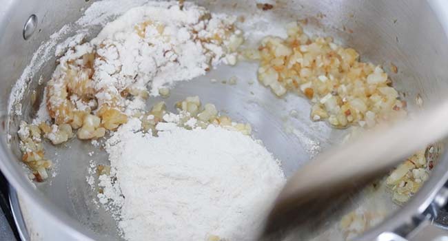 stirring flour into onions and garlic in a pot