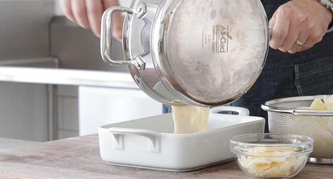 adding cheese sauce to a casserole dish