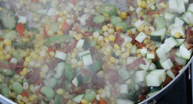 mixing zucchini into corn