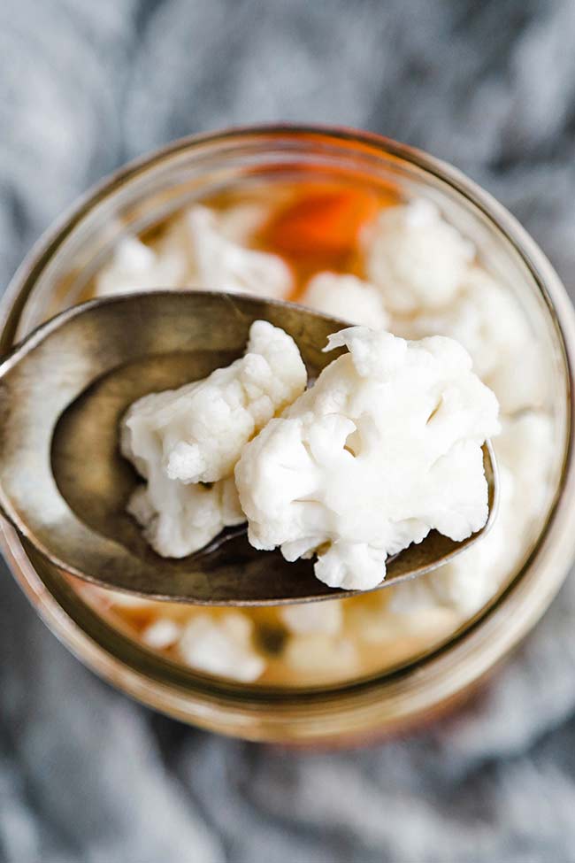 pickled cauliflower on a spoon and in a jar