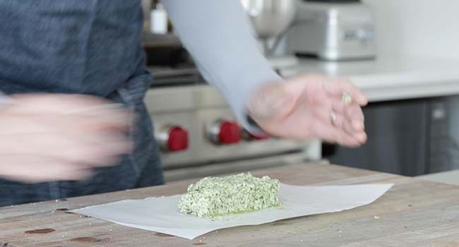adding herb butter to a piece of parchment paper
