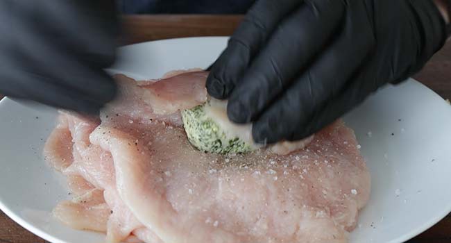 adding herb butter to pounded chicken
