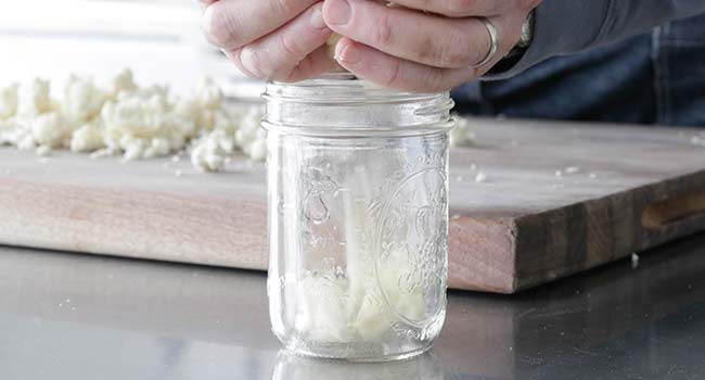 adding cauliflower to a jar