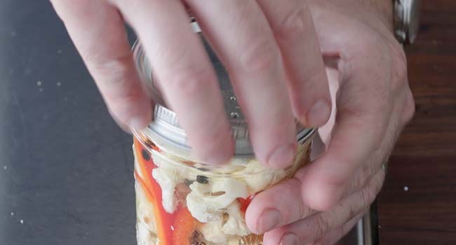 screwing on the lid of a jar of pickled cauliflower