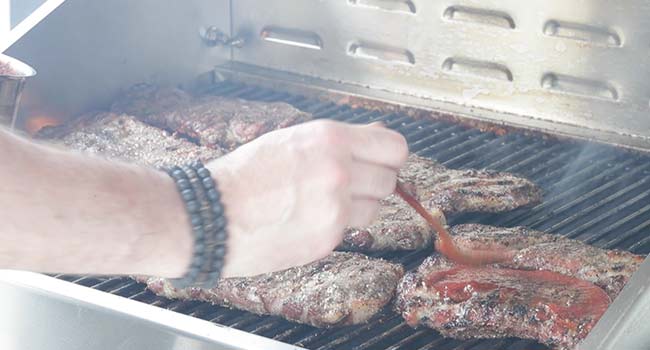 saucing up pork steaks with bbq sauce