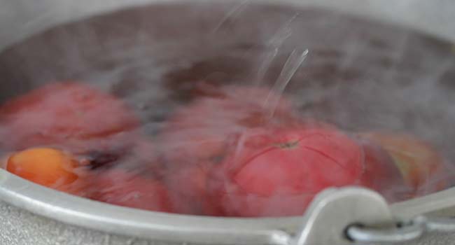adding tomatoes to boiling water