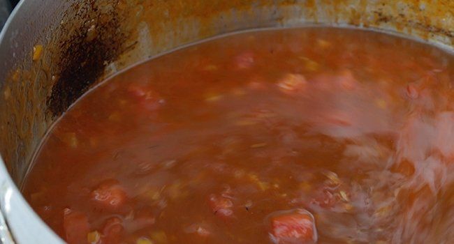 adding chicken stock to cooked tomatoes