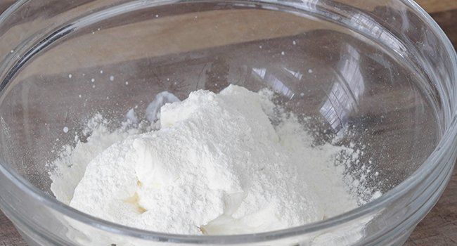 adding flour to a bowl of sour cream