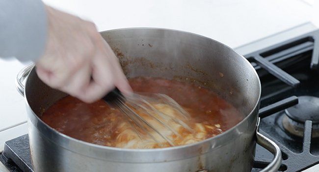 mixing sour cream into a pan with broth
