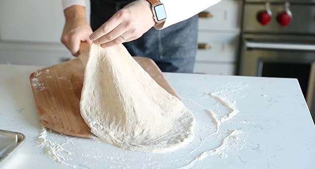 adding pizza dough to pizza peel