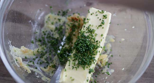 adding herbs and butter to roasted garlic