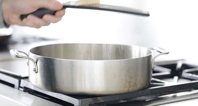 adding parmesan cheese to a pan with zucchini