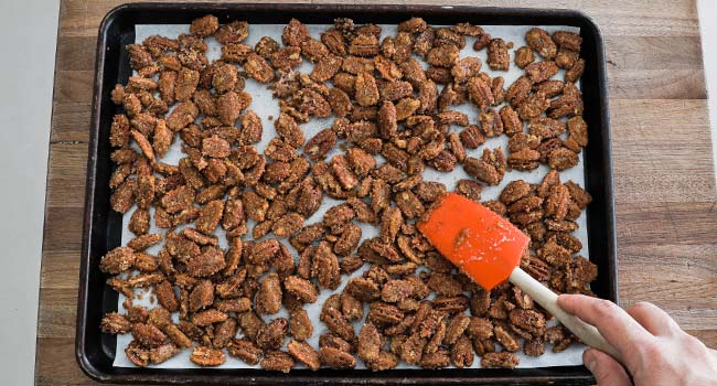 spreading pecans out on a sheet tray lined with parchment paper