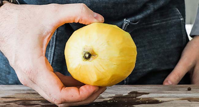 holding a peeled mango