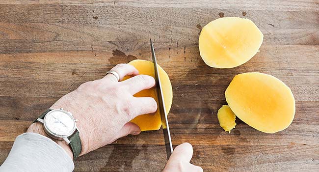 carving the flesh of a mango away from the seed