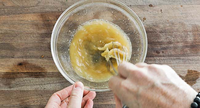 whisking lemon juice, vinegar, and mustard