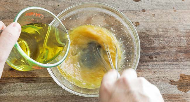 drizzling oil into a bowl while whisking