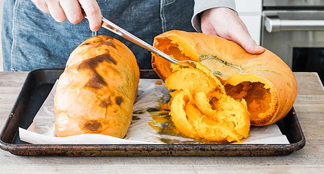 scraping the seeds from roasted pumpkins