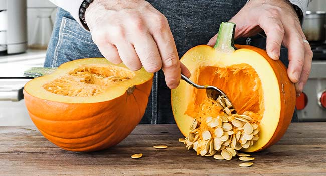 scooping pumpkin seeds out of a pumpkin