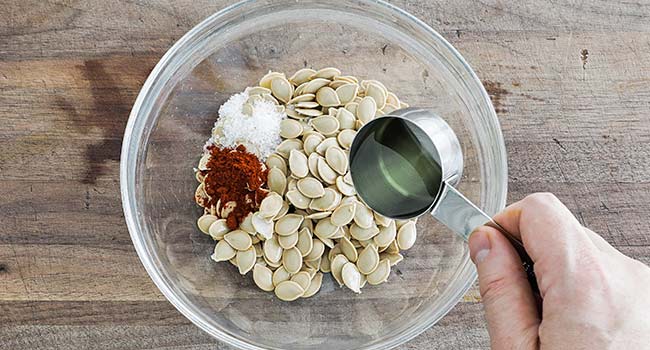 mixing pumpkin seeds with oil and seasonings