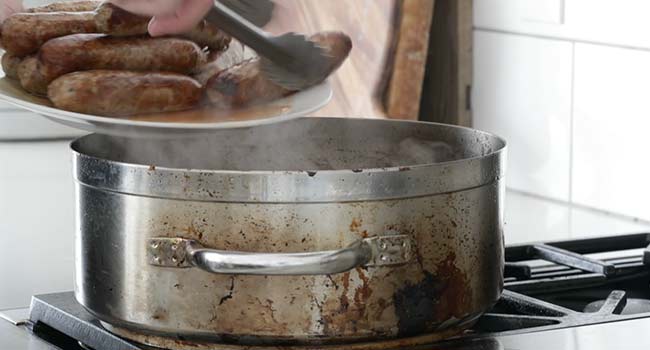 adding sausage to a pan