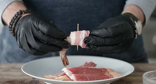 adding a toothpick to bacon-wrapped shrimp