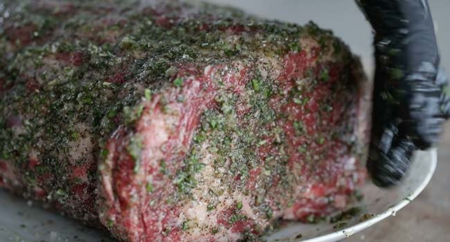 rubbing herbs and garlic all over a prime rib