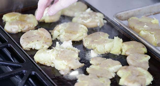 adding butter to smashed potatoes searing