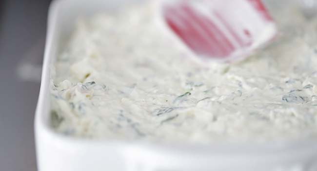 adding the artichoke and spinach dip to a dish