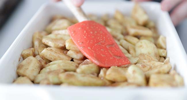 adding spices apples to a casserole dish