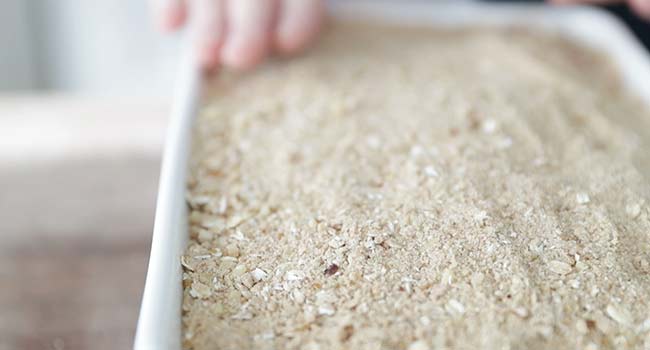 flattening out a streusel in a casserole dish