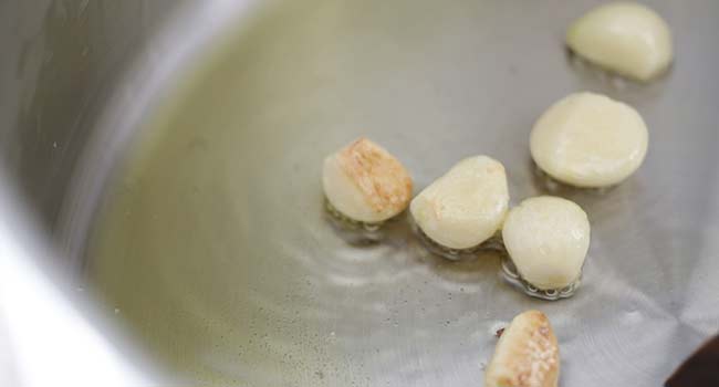 sautéing garlic cloves in a pan