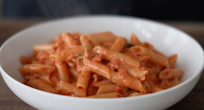 adding penne alla vodka to a bowl