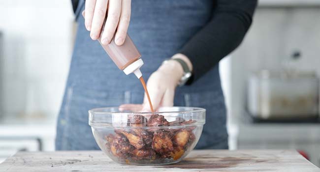 adding bbq sauce to smoked chicken wings