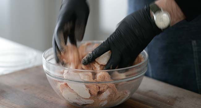 tossing chicken wings in a bbq rub