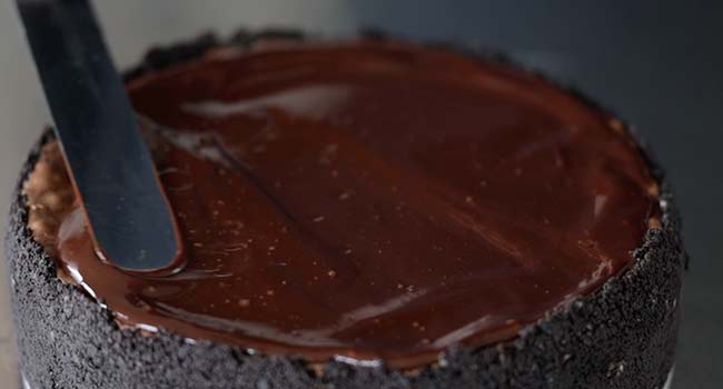 adding melted chocolate to a chocolate cheesecake