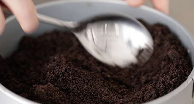 adding oreo crumbs to a pan