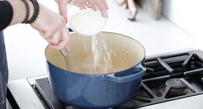 adding flour to a pot