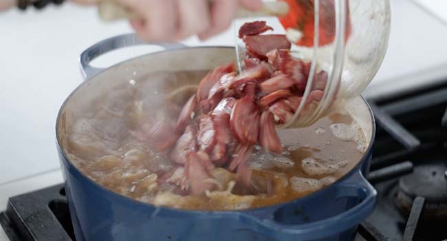 pouring sausage to a pot with stock