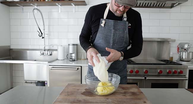 adding shredded potatoes to a bowl