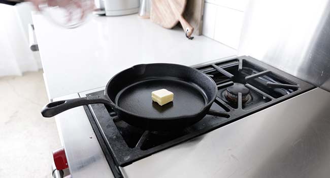 adding butter to a cast iron skillet