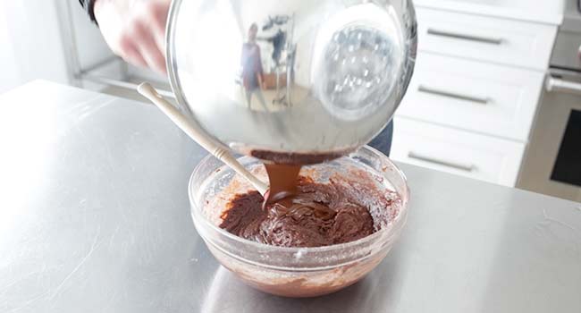 adding melted chocolate to a brownie batter