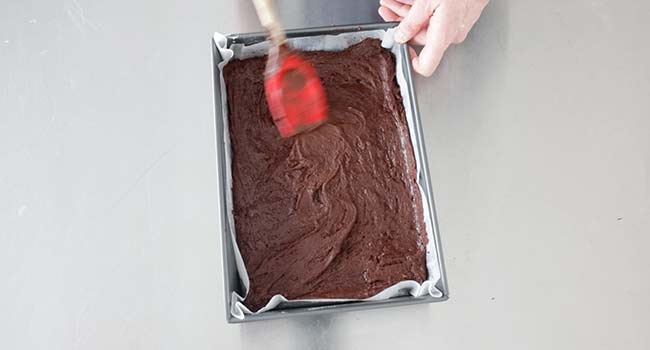 smoothing out brownie batter in a pan