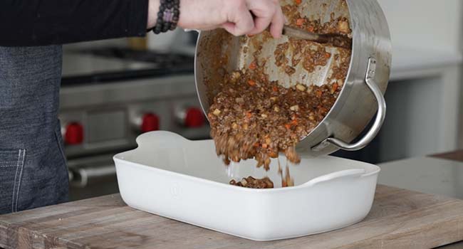 adding cottage pie filling to a casserole dish