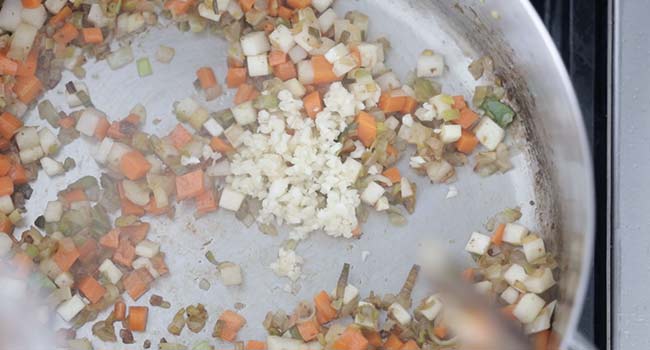 adding garlic to cooked vegetables