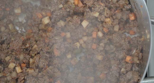 mixing in tomato paste to beef and vegetables