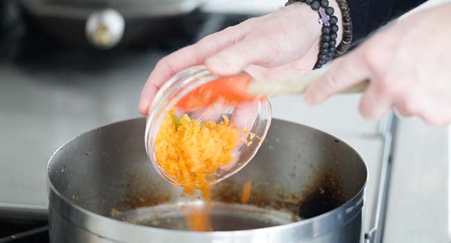 adding shredded carrots to a pan